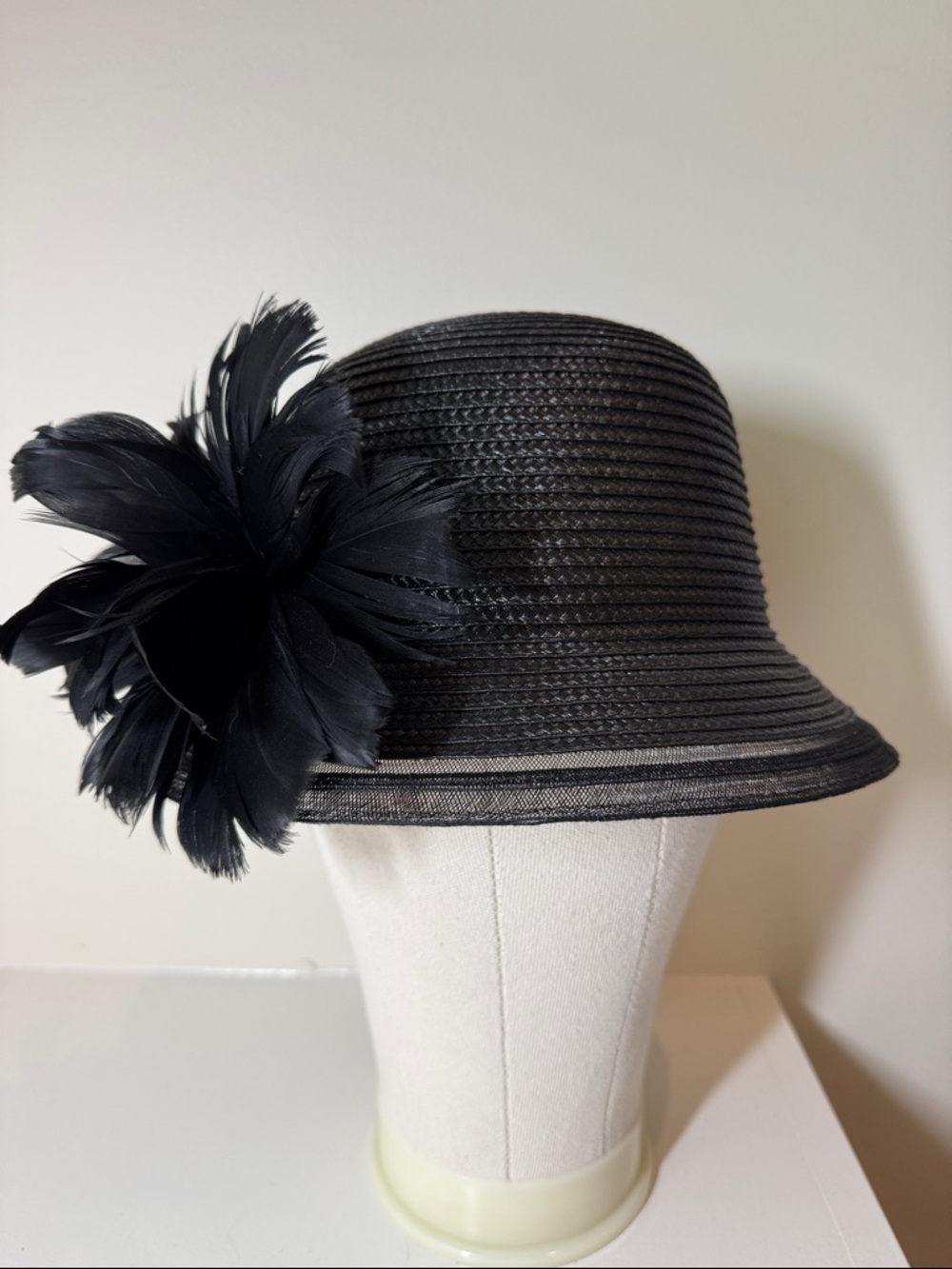 August black poly straw hat with feather adornment and decorative edge. M.